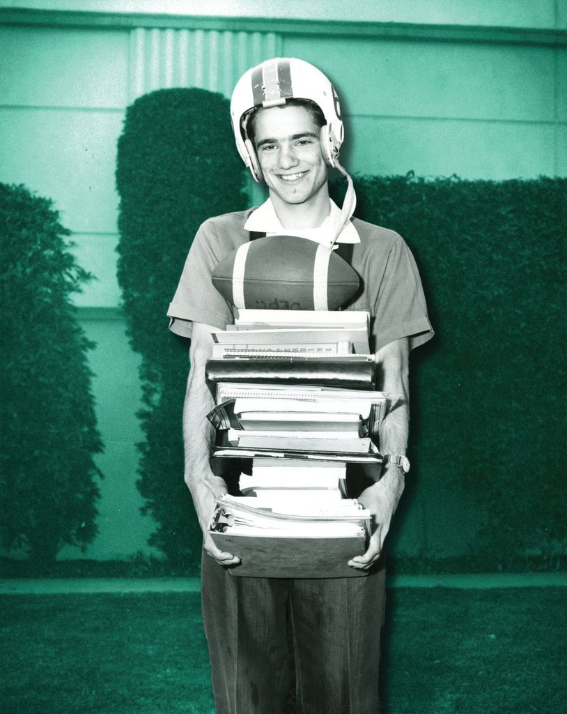 Stu_Warford_with_many_books_and_wearing_a_football_helmet