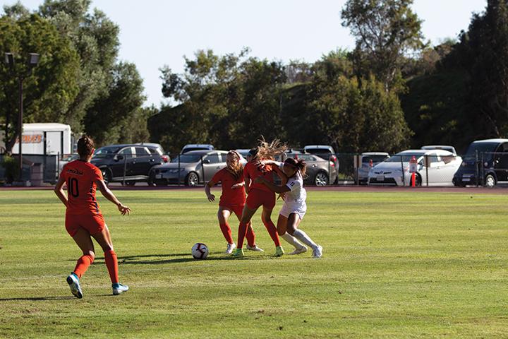 The Women's Soccer defense works to clear the ball during a 2019 match. This fall, the Waves have had to build team chemistry over Zoom meetings rather than on the field. File photo