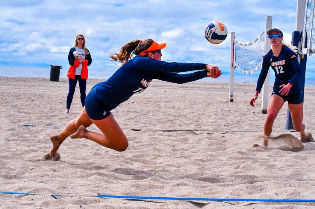 Graduate student Carly Skjodt leaps for a dig during a 2019 match at Zuma Beach, while her partner Sutton Mactavish looks on. Photo courtesy of Pepperdine Athletics