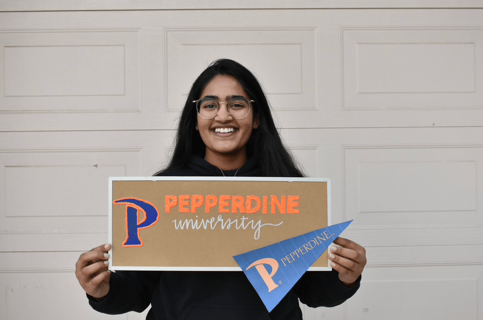 Kurapati holds a Pepperdine sign and pennant to celebrate her admission to Seaver College's Biology program in May at her home in Thousand Oaks. Kurapati said she is very interested in science, and loves that the field constantly changes.