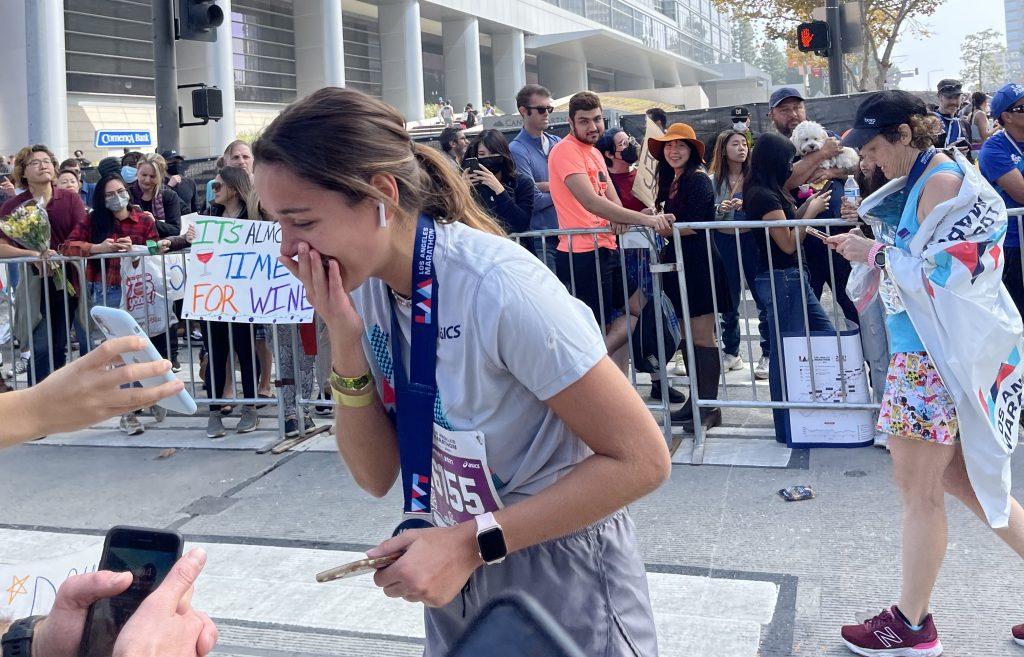 De La Flore cries as she crosses the finish line of the LA Marathon and sees her end time. After completing the run in just under five hours, De La Flore said she was met with signs and flowers from her friends.