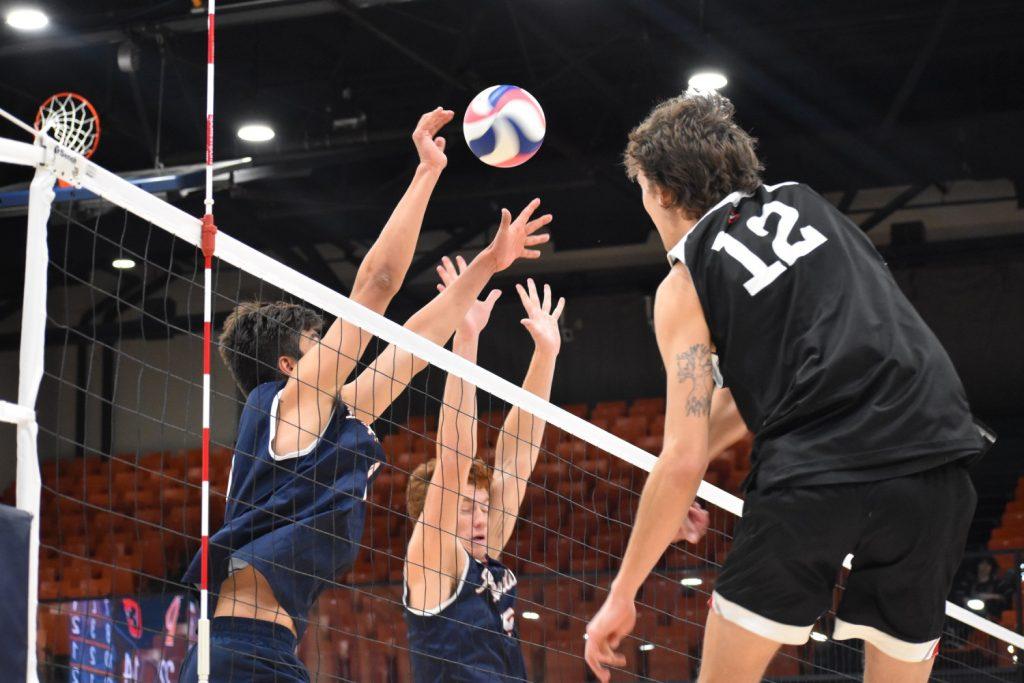 Sophomore middle blocker Andersen Fuller joins sophomore setter Bryce Dvorak for a double block.  As a setter, Dvorak has dominated the front line with 26 total blocks this season.  Photo of Marie Elisabeth