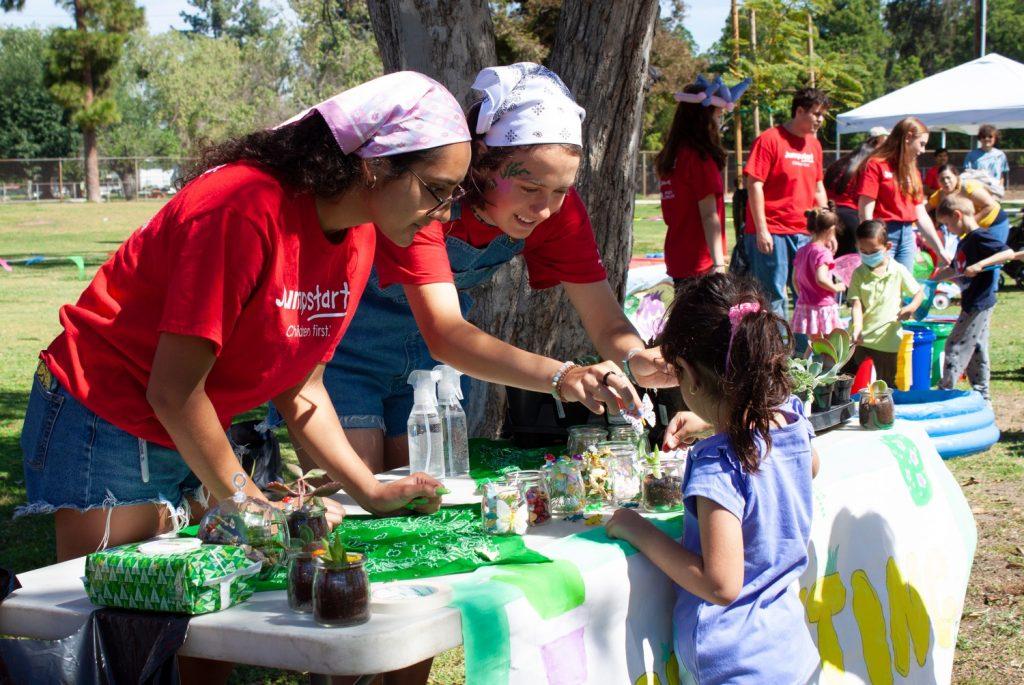 Jumpstart members at the planting booth teach a young girl how to plant a succulent. Rouse said the children will carry the practical skills they learn at each booth into their adult lives.