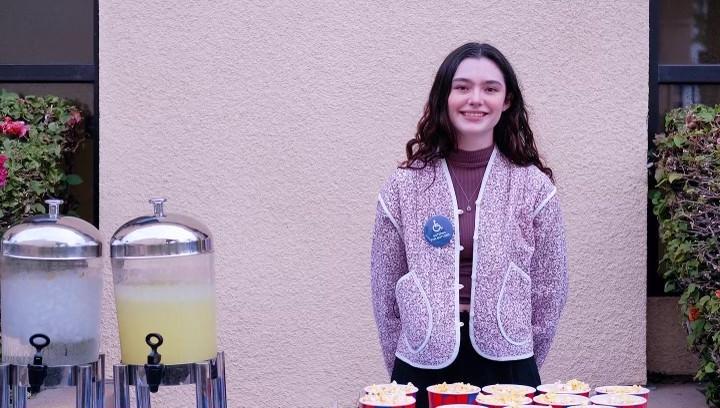 Sophomore Maddie Beadle, wearing a Buttons for Buttons pin, hands out popcorn during "Crip Camp" screening for Disabilities Awareness Week in March 2022.