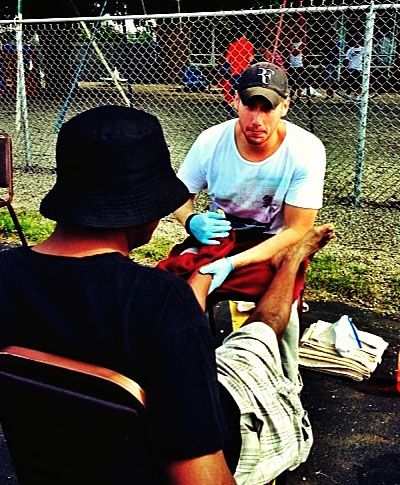 Senior Andrew Enslen, as a Happy Feet Clinic volunteer, washing a man's feet in August 2013. (Photo by Miles Miller)