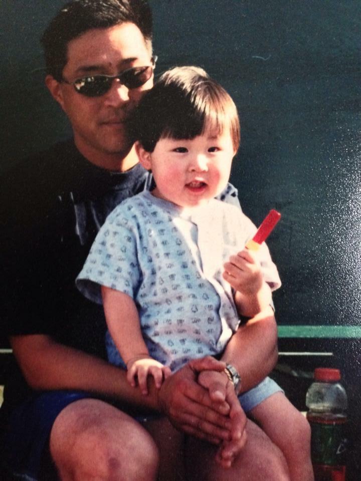 Justin sits in his father's lap as a young boy.