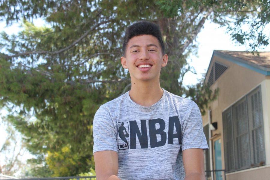 Jarret smiles during an outdoor photoshoot while donning an NBA t-shirt to signify his love for the sport.