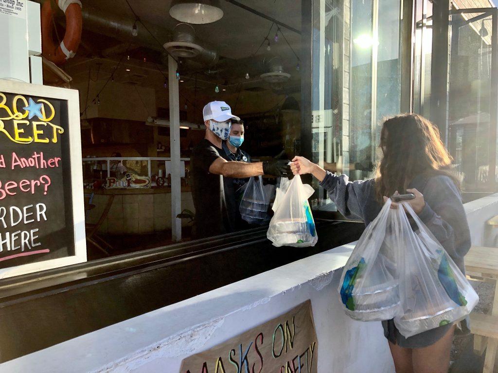 A customer picks up her food from the takeout window at Broad Street Oyster Company.