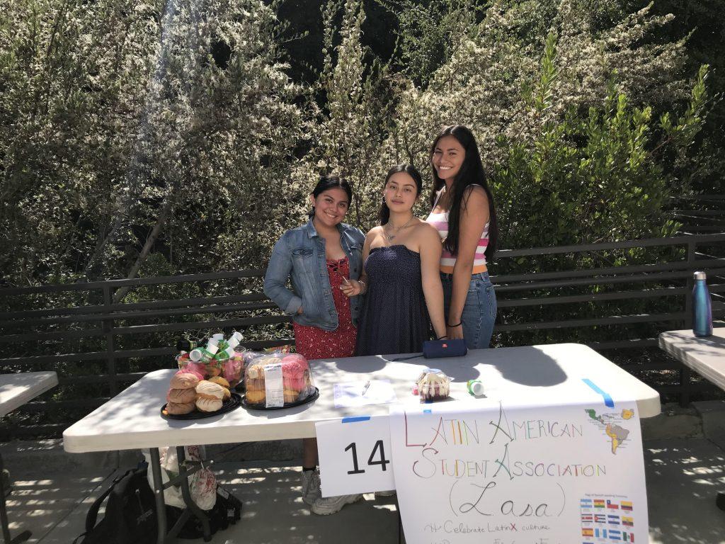 Taura (far right) and her fellow co-presidents stand behind their booth for the Latin American Student Association at their high school club fair. Taura handed out pastries and candy while encouraging fellow students to join the club.