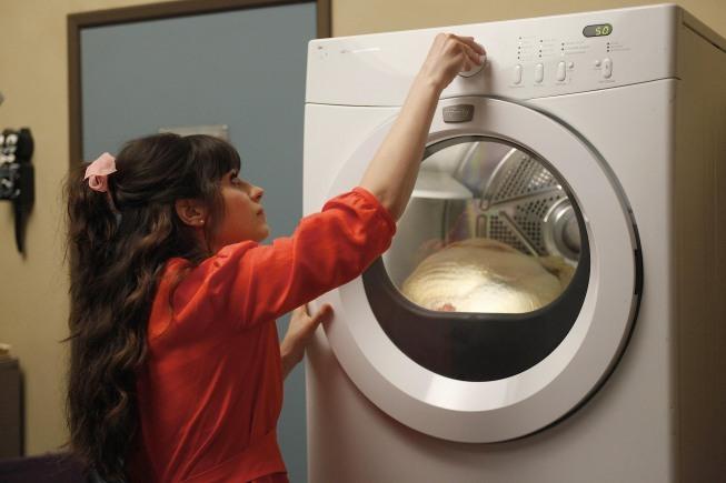 Jess, played by Zooey Deschanel, loads a frozen Thanksgiving turkey into the dryer. The holiday's main entree did not fit into the apartment's oven. Photo courtesy of IMDb