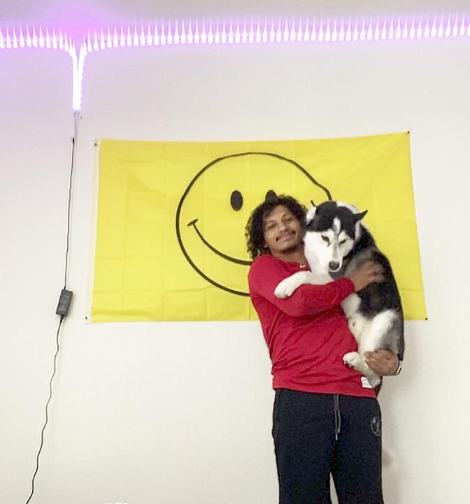 McAfee cradles his husky, Halo, in front of a smiley-face flag in his Arizona apartment on Sept. 15. He said the flag is the first thing he looks at every day, which makes him smile. Photo by Ali Levens