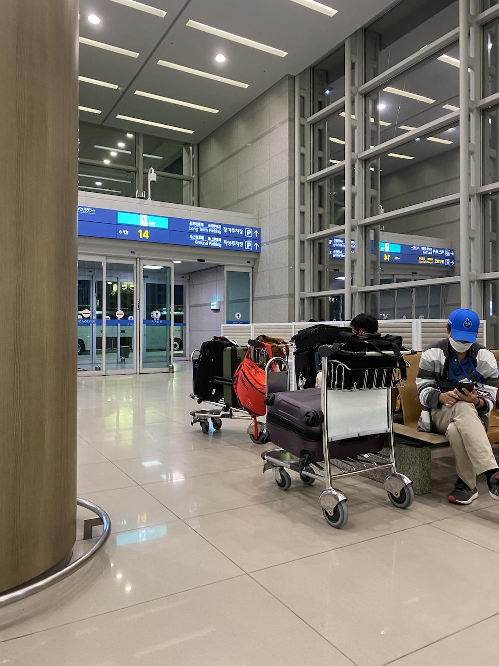 Two men wait with their luggage for the government-provided bus at 7:50 p.m. The bus took our group from ICN airport to the Benikea Hotel in Seoul.