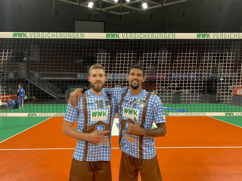Wieczorek (left) poses with teammate Jalen Penrose in front of the net in their lederhosen jerseys while playing in Munich's Audi Dome in September. The lederhosen jerseys became popular in the volleyball community across Europe. Photo courtesy of Dave Wieczorek