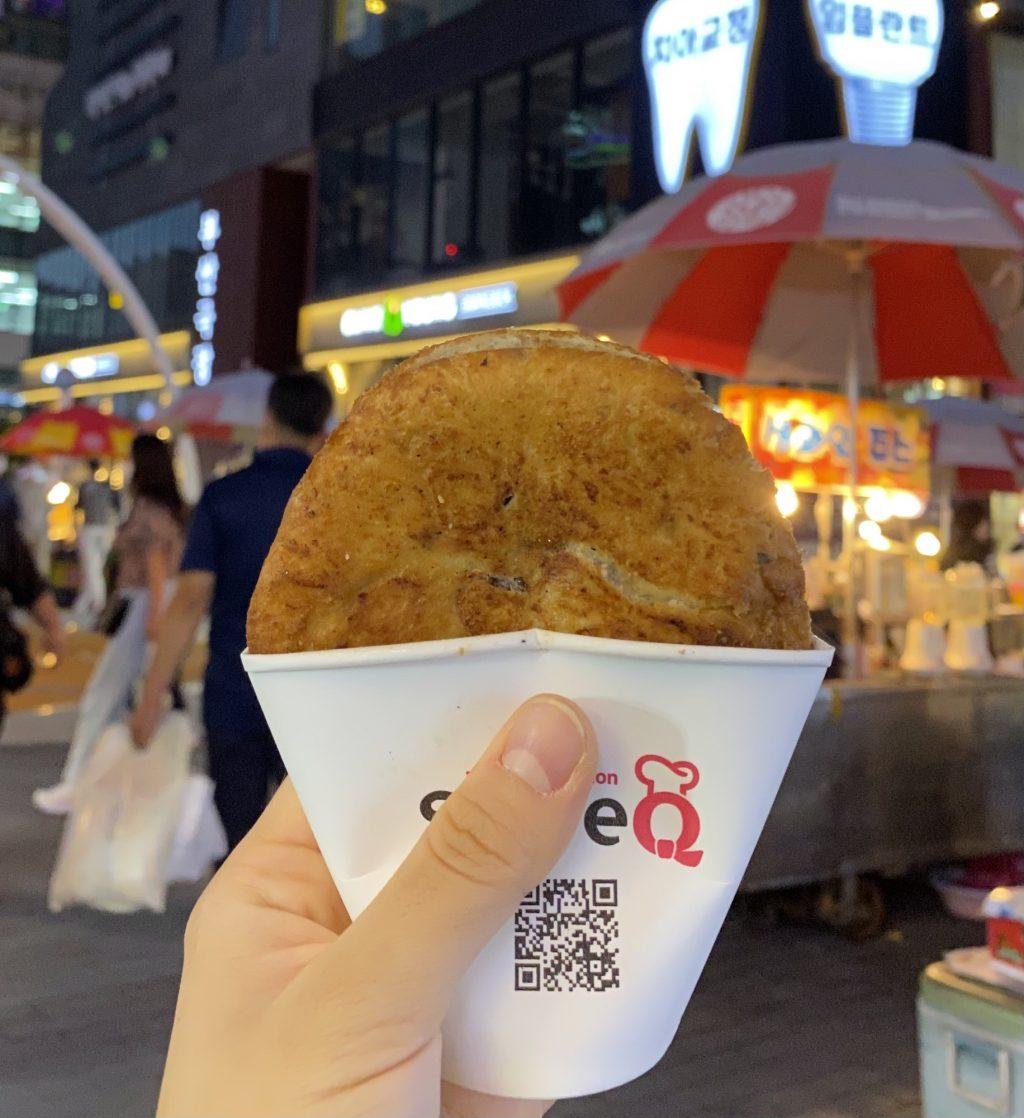 I hold a hotteok, a fried Korean dessert made out of dough, brown sugar and honey, at the Hirang Street Open Market on Oct. 4. Dozens of street food stands sold different types of Korean food at the market.