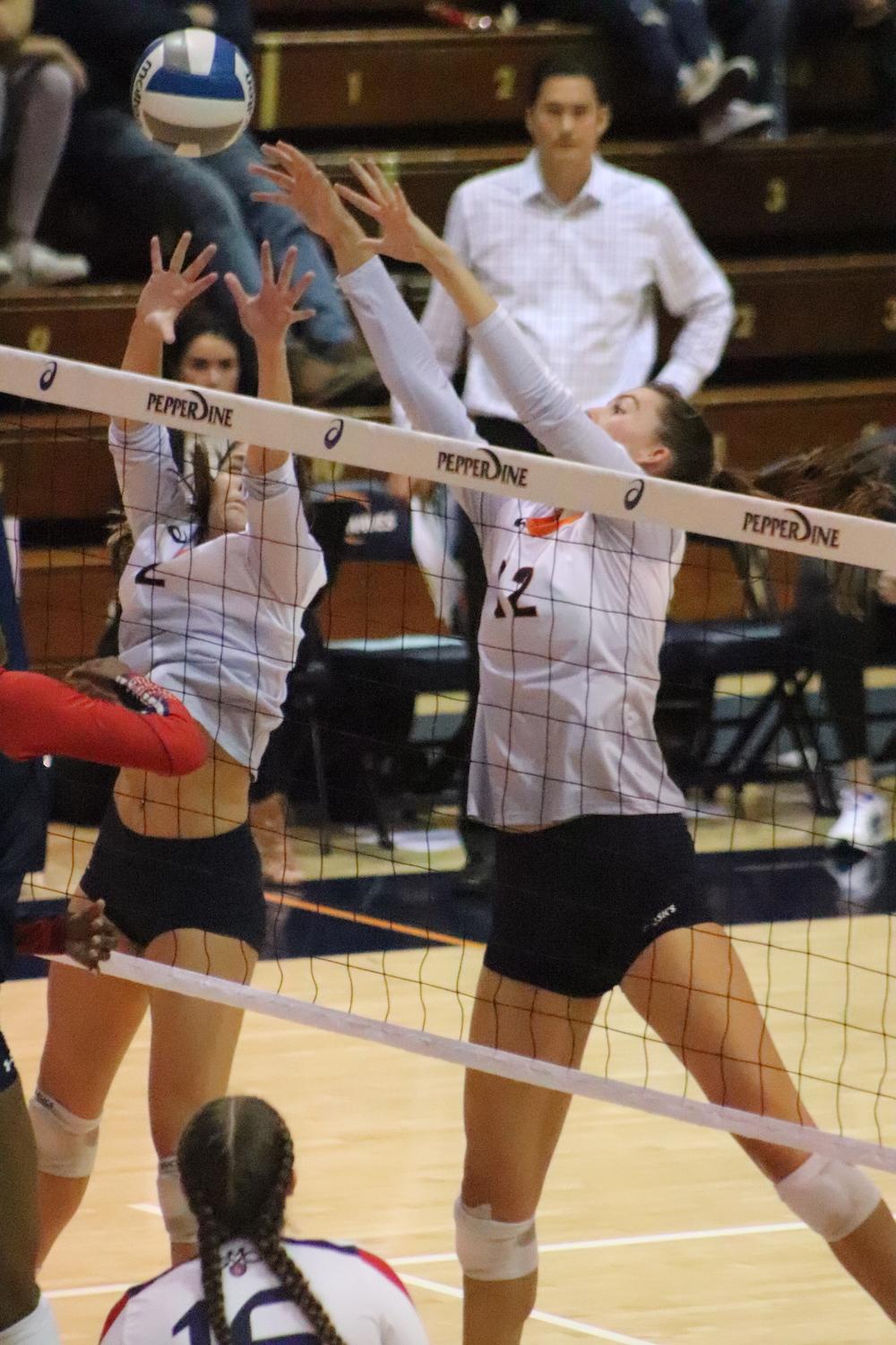 Head Coach Scott Wong looks on as sophomore setter Isabel Zeleya and 2019 senior middle blocker Tarah Wylie go up for a block against Saint Mary's. This fall, Wong entered his sixth season as the head coach. Photo by Ali Levens