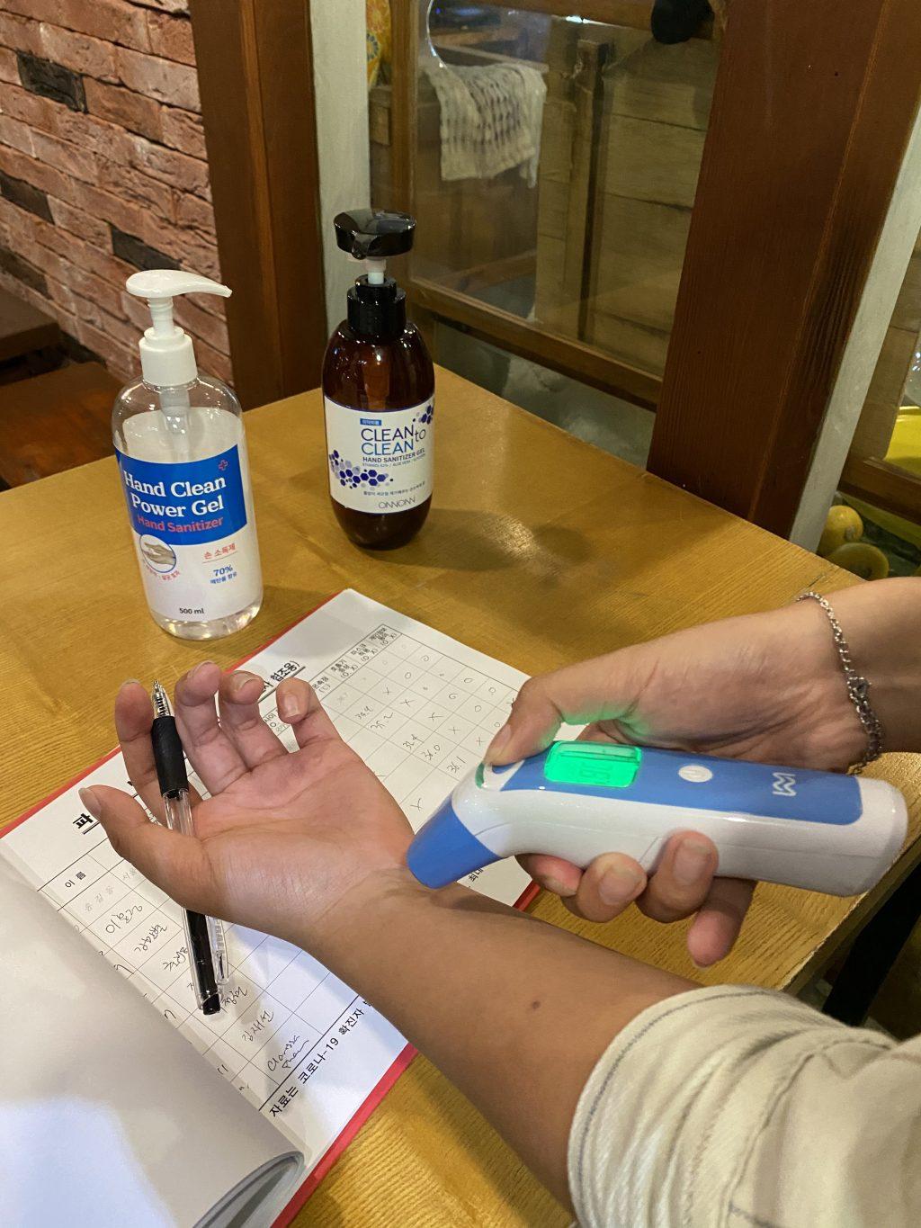 A customer uses the temperature scanner to check that her temperature is under 37.5 degrees celsius. Different facilities implemented varying degrees of the tracking policy, but most stores provided the basic items for customers to self-check and record.