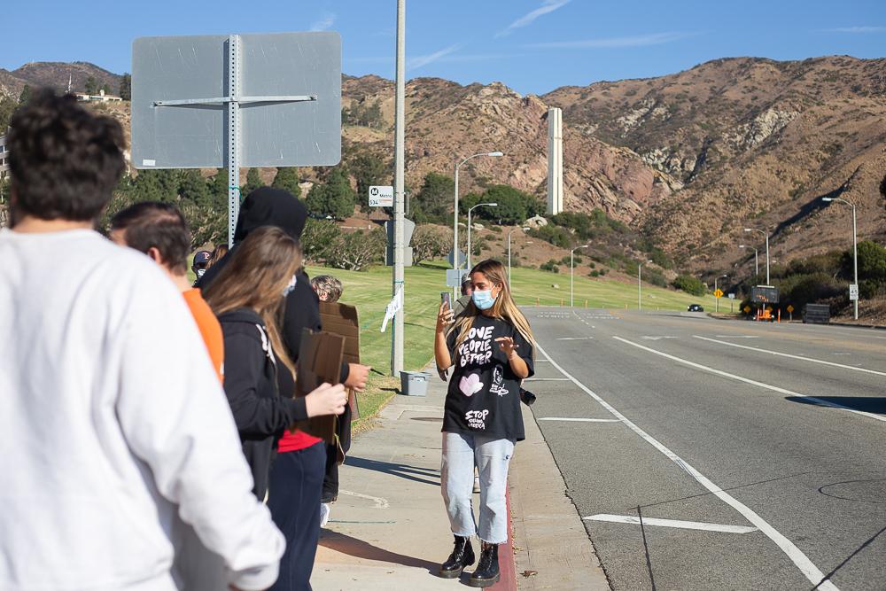 Hope Dease films a group of students protesting on Malibu Canyon Road for Pepperdine Justice Coalition's Instagram live. Dease said seeing the small community protesting Nov. 11, brought her hope. Photo by Ashley Mowreader
