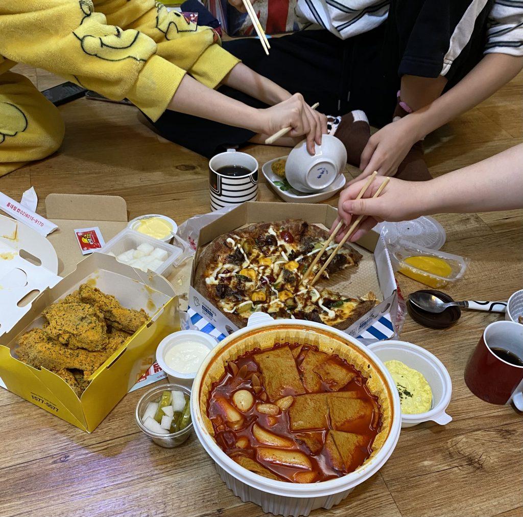 A few of my housemates dig into pizza and fried chicken Oct. 16 at our share house. Feasting from the white bowl, we ate spicy Ddukkbokki, a popular traditional Korean food that consists of rice cakes, fish cakes, eggs, vegetables and the Ddukkbokki sauce.