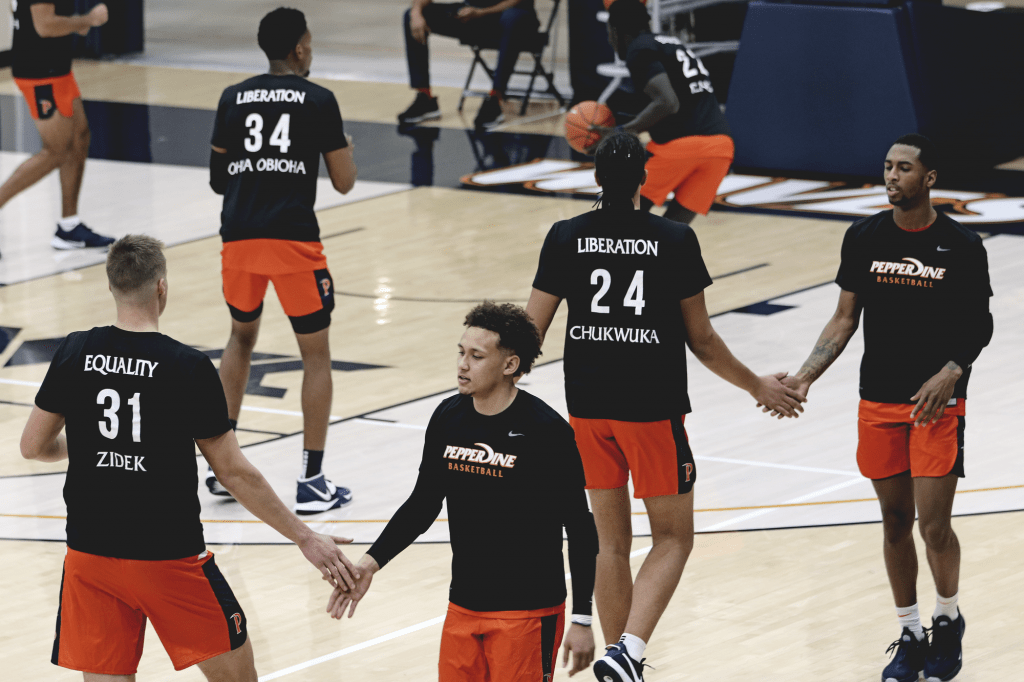 Sophomore forward Jan Zidek high-fives senior guard Colbey Ross and graduate student forward Kene Chukwuka encourages XXX during warmup before defeating Portland.