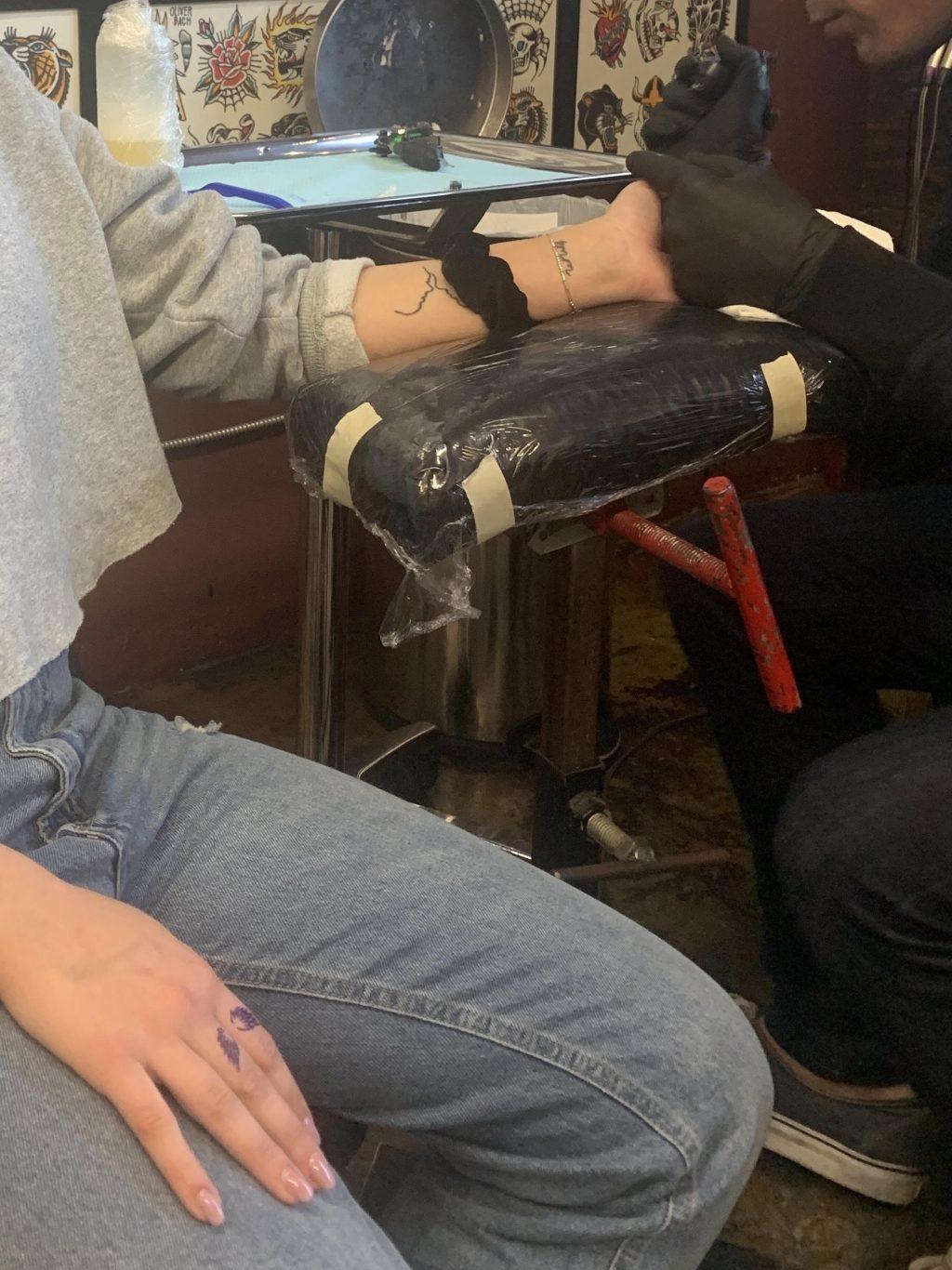 Moore sits for tattoos of angel wings and a little sparkle to be tattooed on her fingers at a shop in Los Angeles in January 2020. Moore said tattoos in LA are some of the most expensive, where minimum payments could range from $80 to $90. Photo courtesy of Marissa Moore