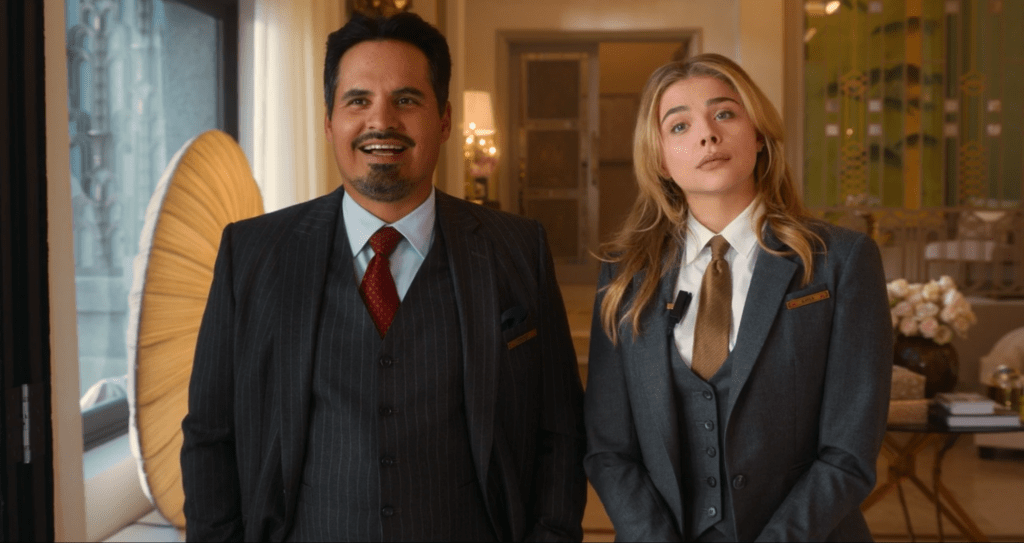Terence, played by Michael Peña, and Kayla, played by Chloë Grace Moretz, discuss wedding plans in a hotel suite. Throughout the film, they stay busy making sure the high-profile ceremony goes just as planned.