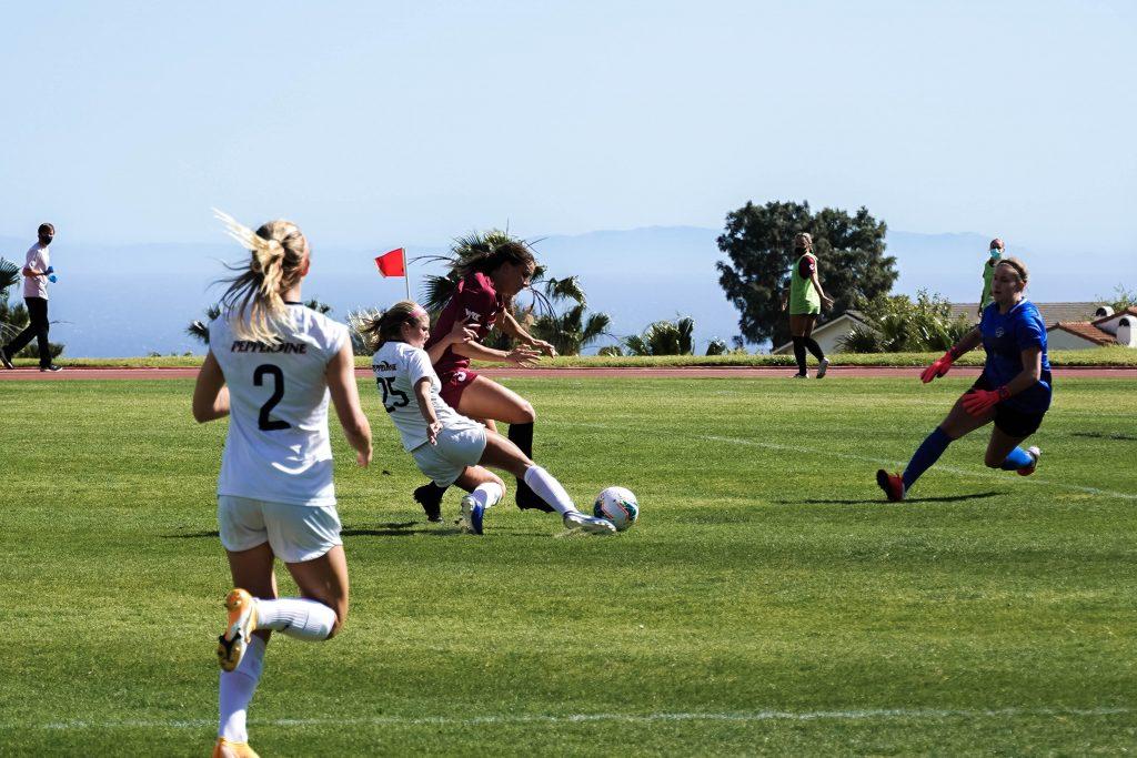 Sophomore forward Shelby Little (No. 25) attempts a sliding shot while guarded by a Santa Clara defender. The Broncos high line forced the Waves to play through balls and try to win footraces to the ball.