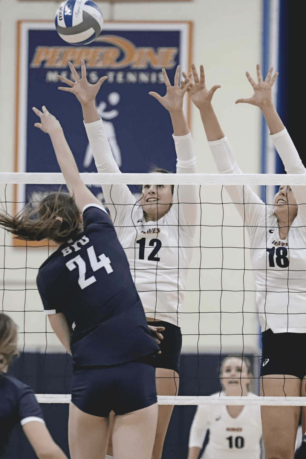Freshman middle blocker Meg Brown (No. 12) and junior outside hitter Rachel Ahrens (No. 18) elevate for a block attempt Feb. 23. Both Waves were named to the 2021 All-WCC First Team.