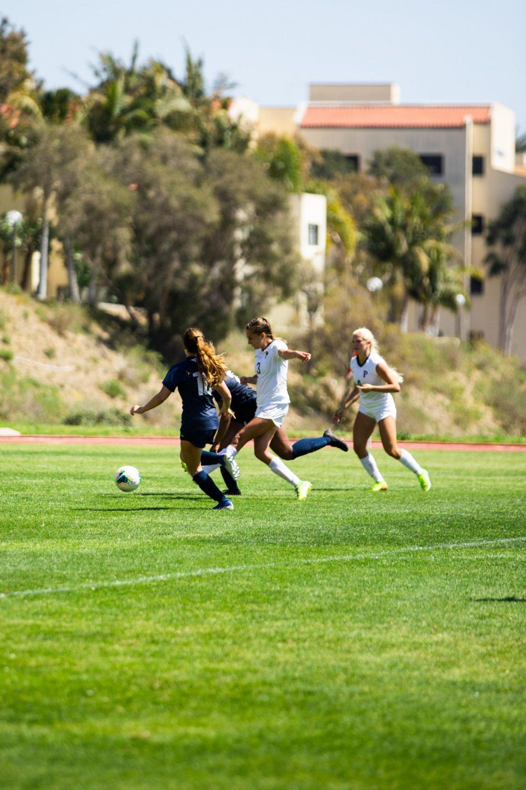 Senior forward Aliyah Satterfield shoots with her left foot between two San Diego defenders in the 88th minute Saturday in Malibu. Satterfield scored on the play, extending the Waves' lead to 7-0.