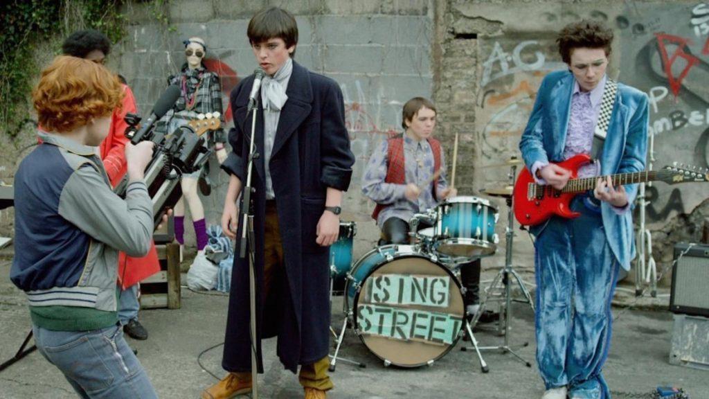 The band, led by Conor, record a music video for their song "Riddle of the Model," the first video they filmed with Raphina. Lucy Boynton played Raphina, and she is also known for her role as Mary Austin in "Bohemian Rhapsody."