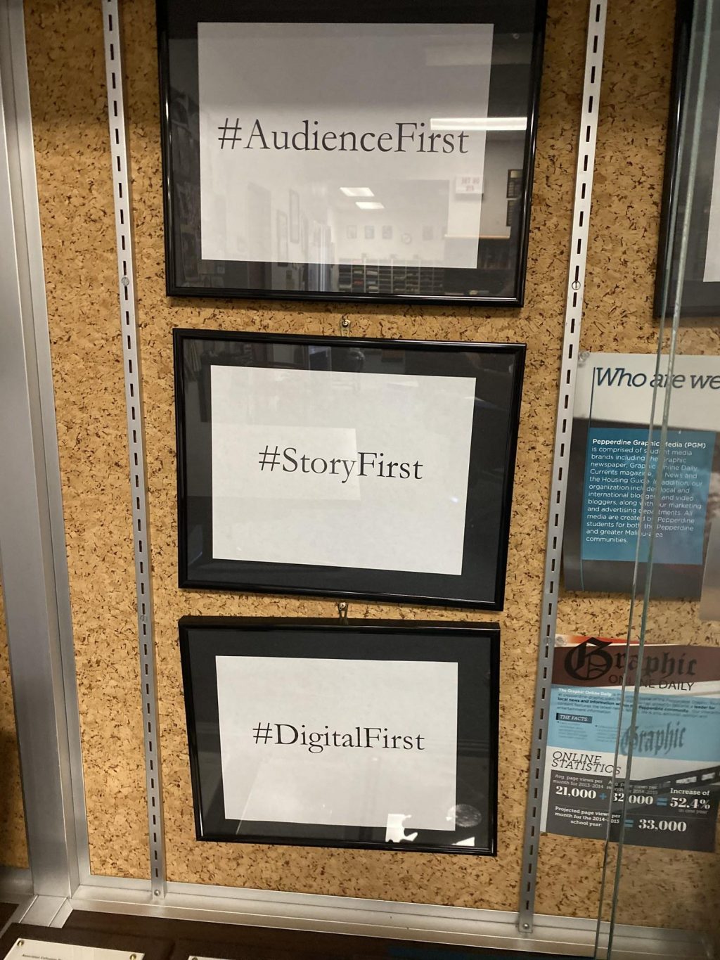 In the Graphic newsroom, a sign that reads "Audience First, Story First, Digital First" hangs in the trophy case. The Graphic shifted to a digital-first model in the 2010s in an effort to make content accessible online for its audience. Photo by Elizabeth Smith