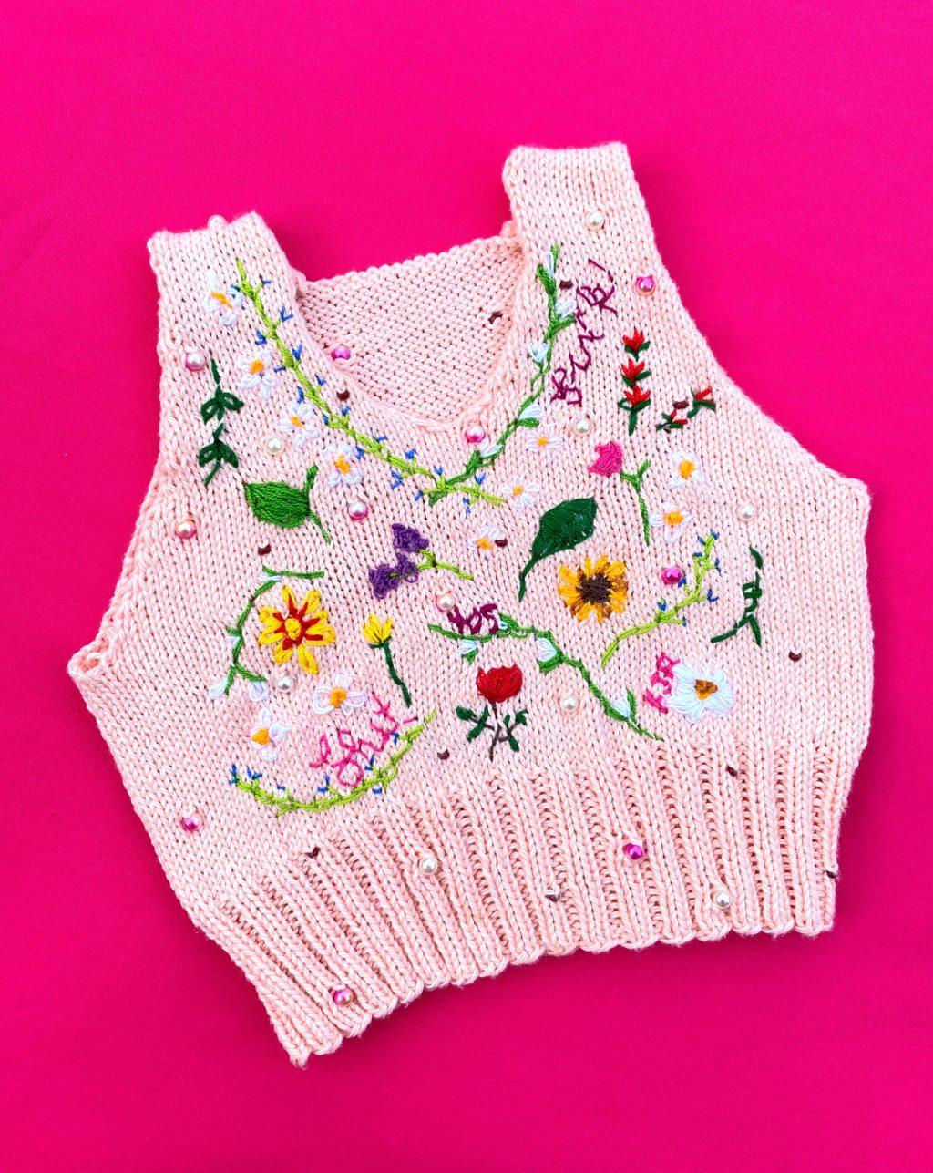 A vest Ross knit in June is photographed on her hot pink kitchen table for an Instagram post that shows off her work. Ross said she has recently started incorporating beadwork into her knitwear, like the floral designs in this piece.