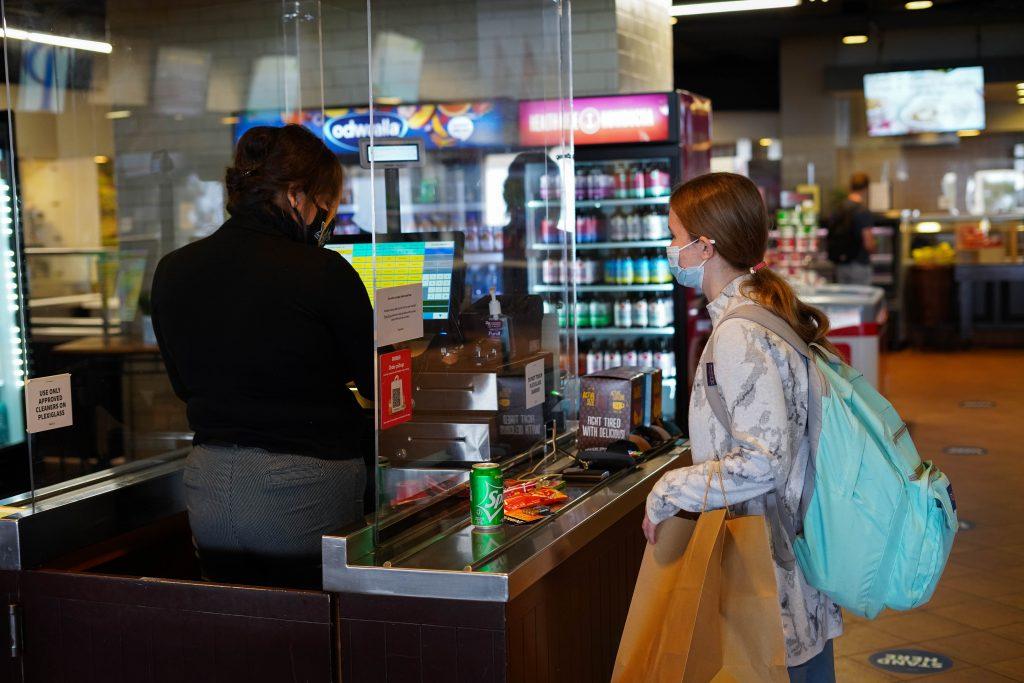 A student purchases a snack from a cashier at the Waves Cafe on June 7. The Caf is open for to-go food service including limited hot daily entree options, grab-and-go sandwiches, salads, fruit cups and desserts.