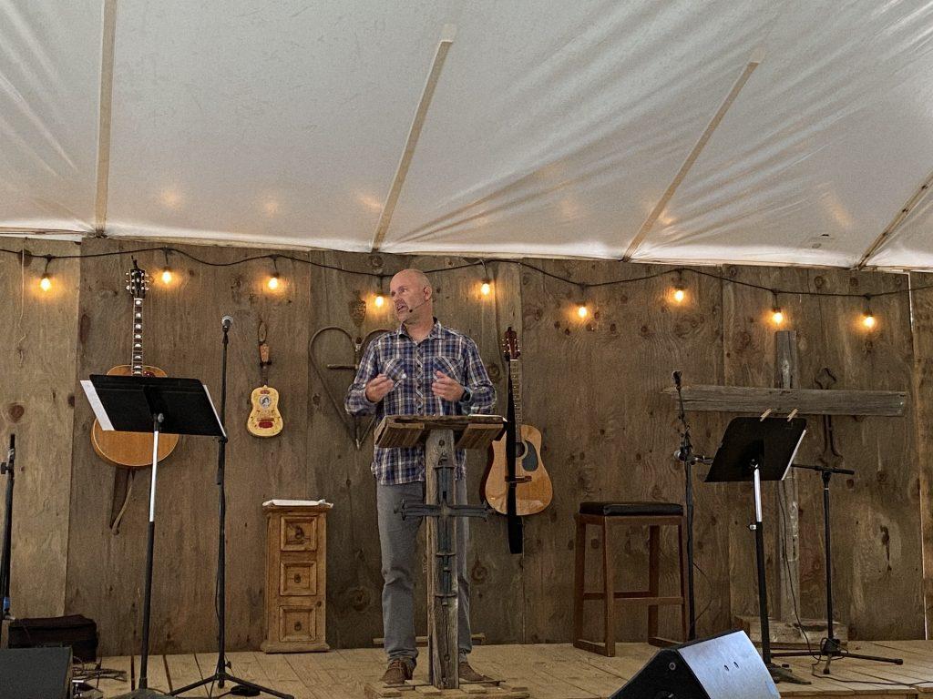 Pastor Brian Kelly speaks to the tent filled with people eager to hear a message, focusing on Acts 20 and the responsibility of loving one another. During the previous school year, the Kellys hosted student nights at their house for the Pepperdine community.