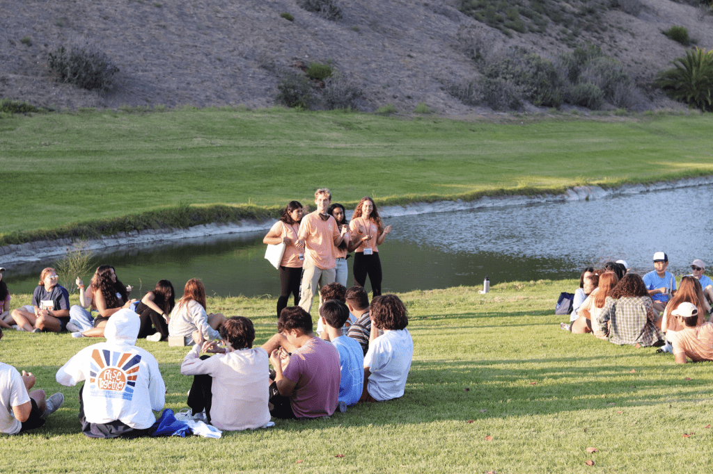 Four Seaside resident advisers lead a group rhythm game on Alumni Park before starting their first Soph Follies practice Aug. 21. There were several bonding games to help the students meet more people. Photo by Ali Levens