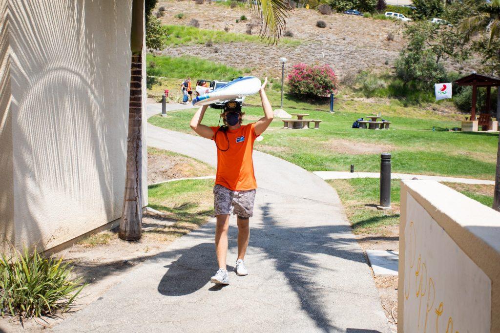 New Student Orientation leader carries in a surfboard for a first-year student moving into Fifield. NSO leaders helped students move in and get settled on campus. Photo by Ryan Brinkman