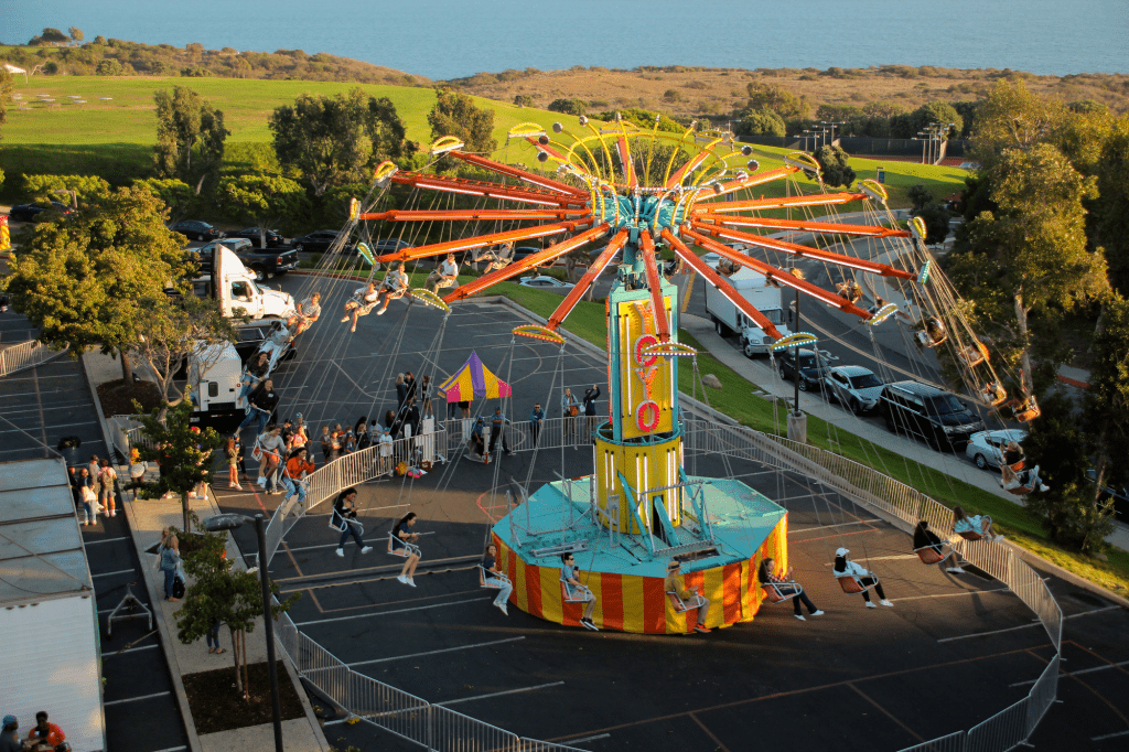 The carnival swing flies over the Firestone Fieldhouse parking lot at Madness VIllage. Madness Village had a Sizzler ride, a Ferris wheel, student activity vendors and free food to celebrate Waves Weekend. Photo by Ella Coates