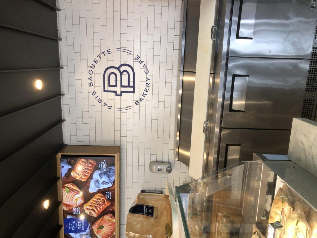 The Paris Baguette logo and tiled wall invite customers into the bakery. Paris Baguette currently has over 4,000 locations globally, according to the business's LinkedIn page.