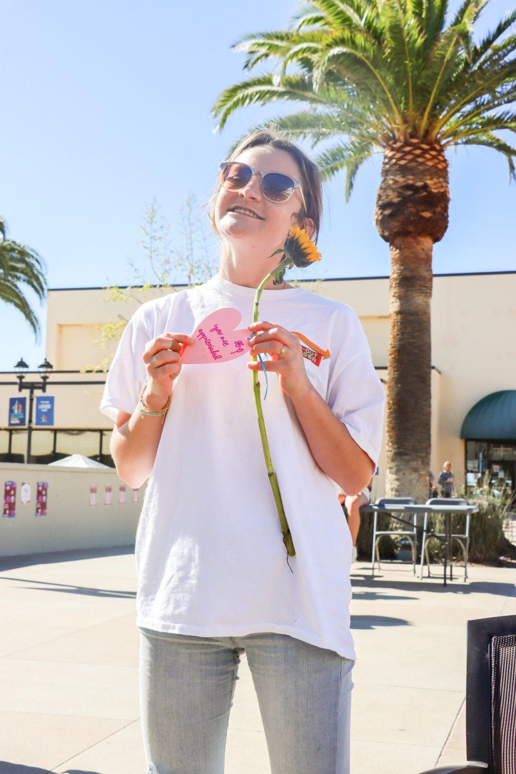 Junior Emma Rydholm holds her sunflower with a kind note on it from SWAB. Junior Healthy Communities ambassador Mallory Finley said seeing "Love Your Body Week" bring joy to students was rewarding. Photo by Sammie Wuensche