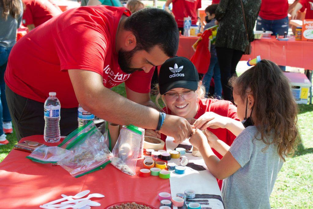 Russell, alongside one of her Jumpstart team members, helps a preschooler craft a music maker using household objects. The children not only have a chance to advance their art skills but also their musical abilities.