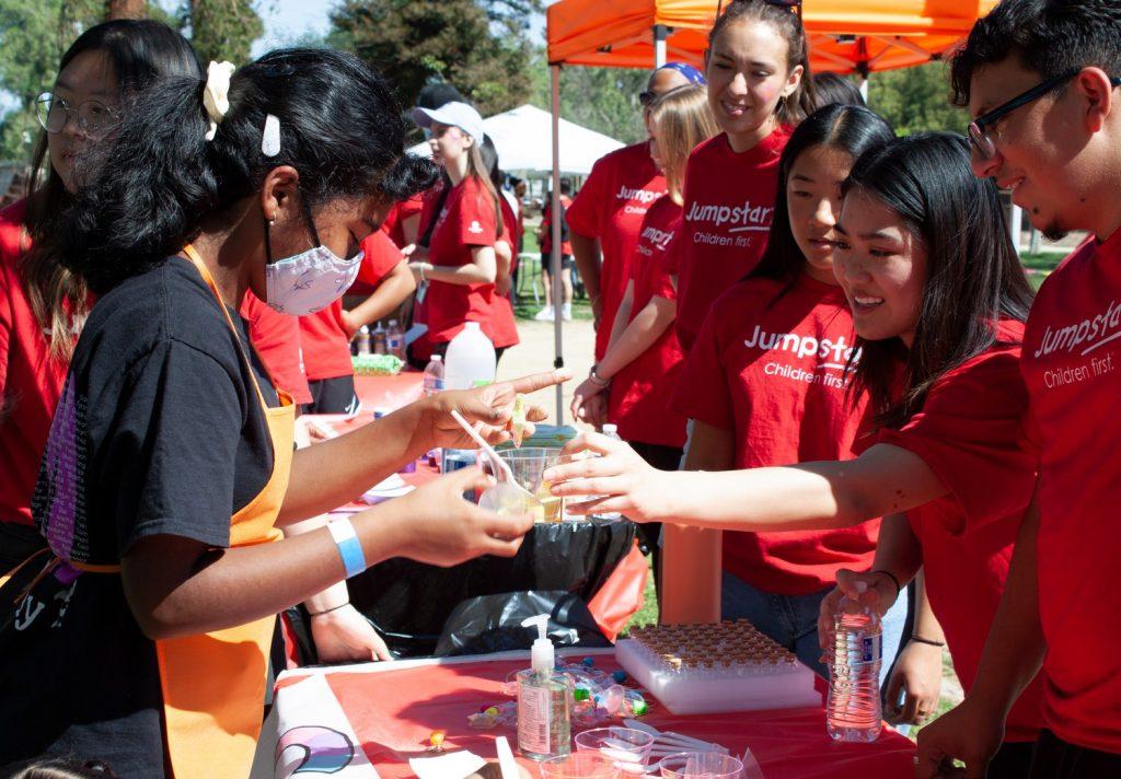 Jumpstart members at the Sand Art booth help a young student make a sand creation. Through these hands-on learning activities, students are able to develop their artistic skills.