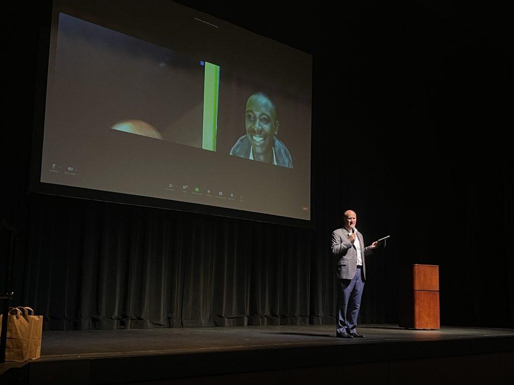 President Jim Gash stands on stage in Smothers Theatre while on a Zoom call with Tumusiime after the screening. Tumusiime joined the Zoom call from his home in Uganda to talk about his life now. Photo by Audrey Geib