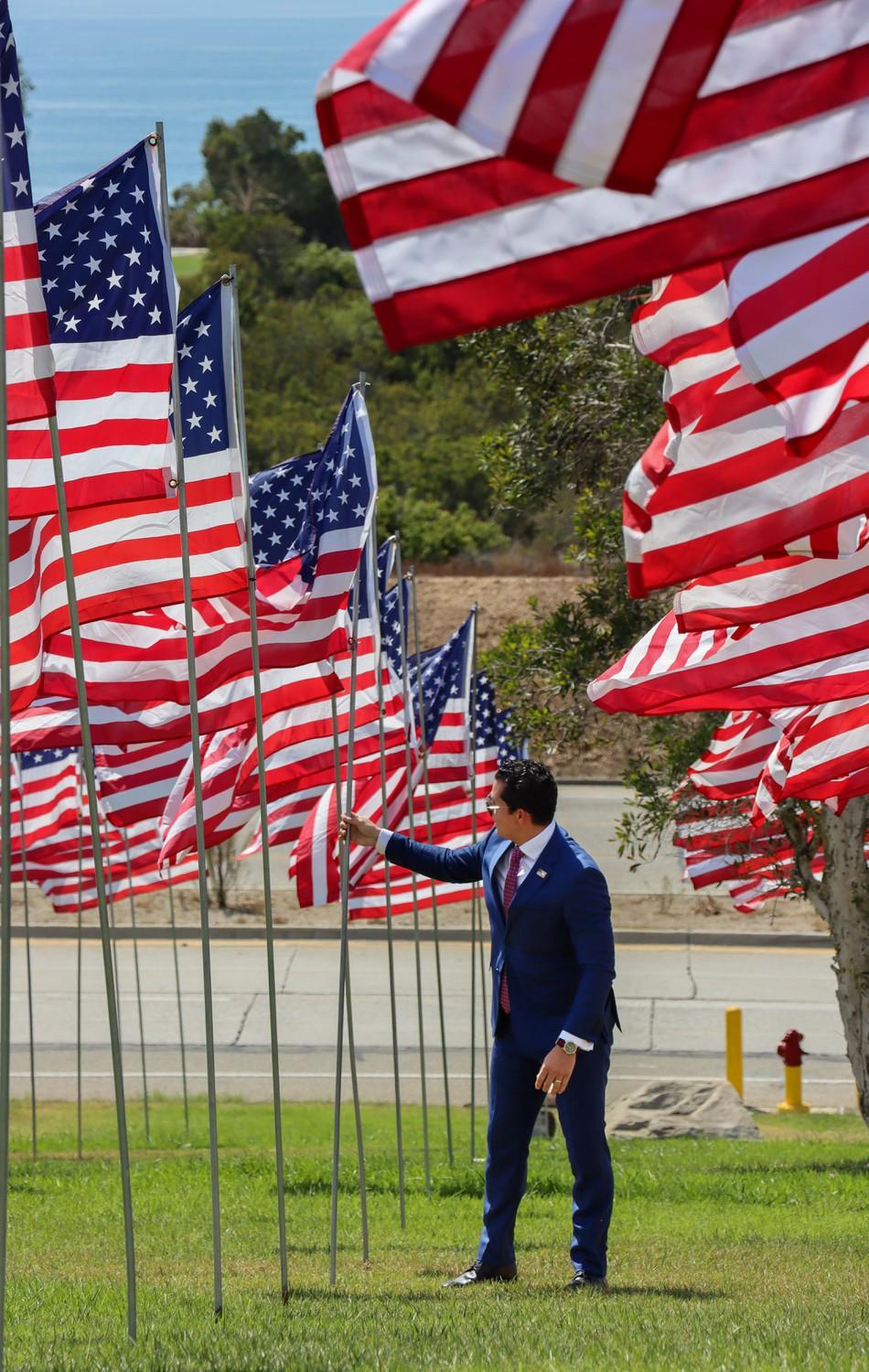 [name], one of the founders of Waves of Flags, adjusts one of the flags that had been tilted