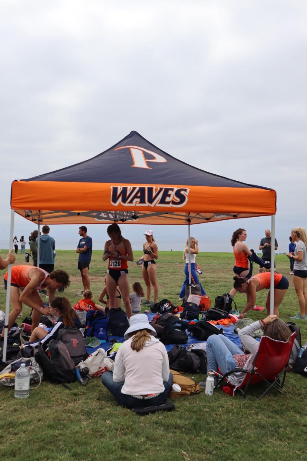 The Pepperdine Cross Country team gathers underneath a tent at the Waves Invitational. The women's team made history with their first ever victory at the Waves Invitational.