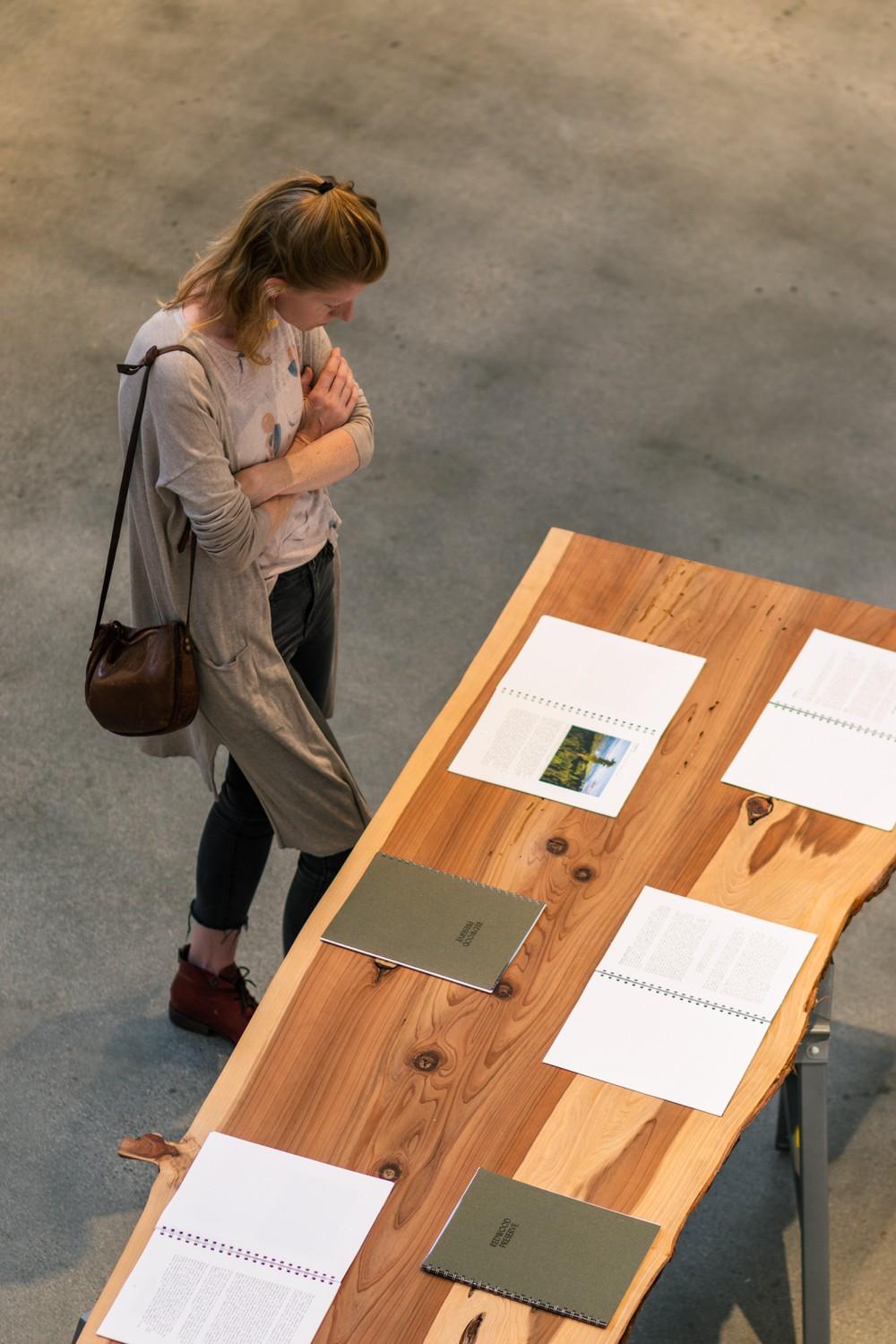 An event attendee stands over the redwood slab table while inspecting the Deep Ecology Project Redwood Preserve on Sept. 10. The table was made of a slab of Redwood to connect the viewers to the trees that the report talked about.