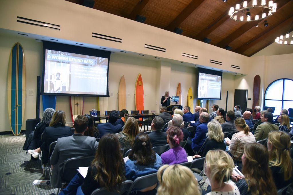 Photo of symposium crowd. Hook is lecturing on her research.