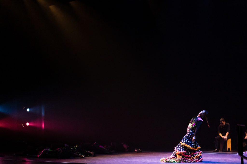 A "bailaora" (female flamenco dancer) leans backward in a colorful "falda" (flamenco skirt) as the remaining troupe members support her solo performance low to the ground in Smothers Theatre on March 21. The company wore dark clothing with bright accents to make their movements stand out from all angles.