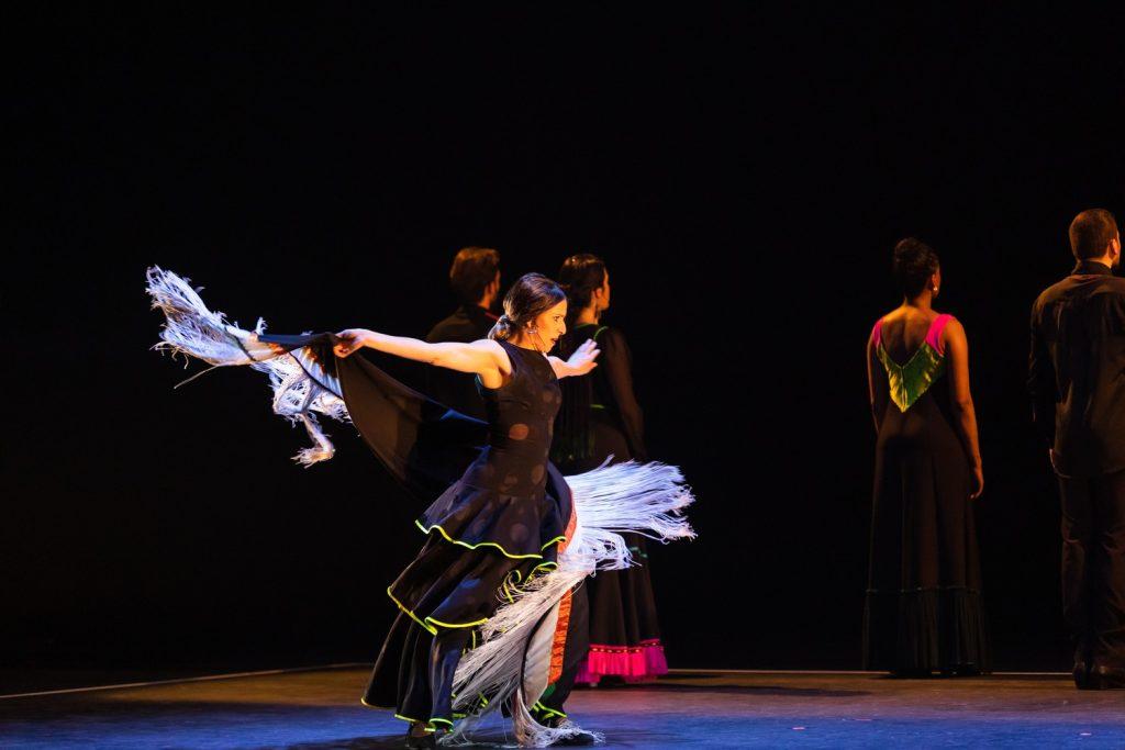 A bailaora (female flamenco dancer) fans her arms behind and moves her tasseled falda (flamenco skirt) as the rest of the troupe turns behind her at Smothers Theatre on March 21. Flamenco dancing resulted from the Roma migration to Spain in the ninth century, according to Britannica.