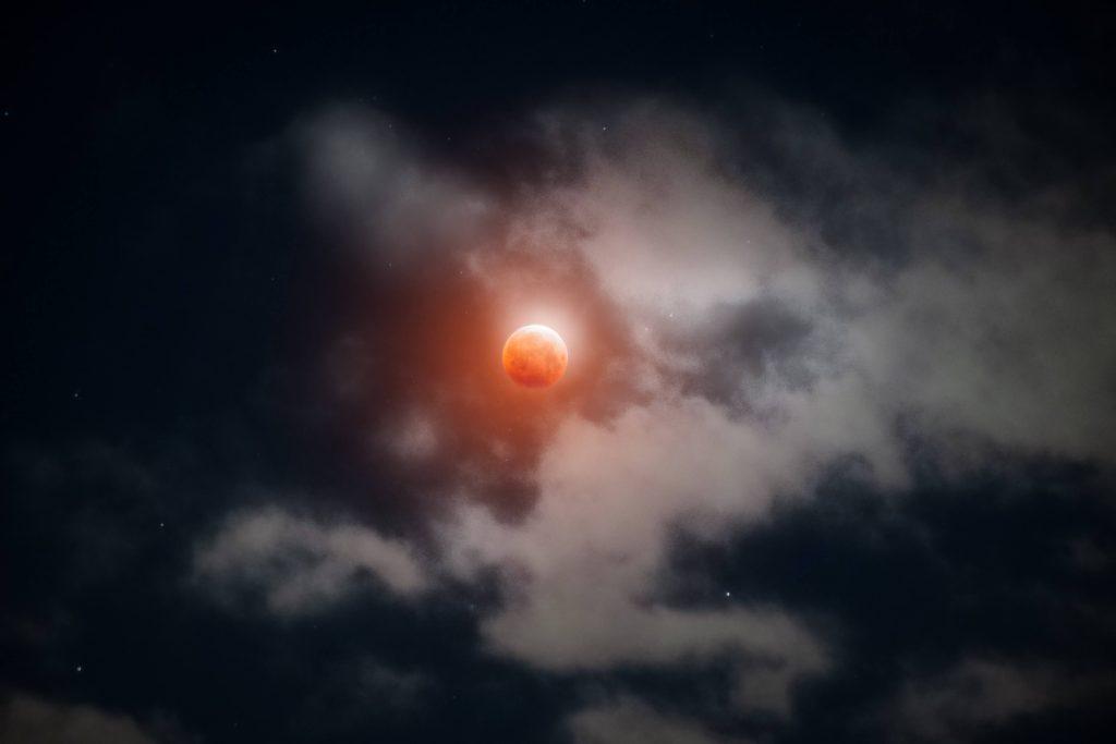 The moon, glowing red from the Earth's shadow, peaks out from the clouds in Portland, Oregon, early in the morning of May 26, 2021. When I woke up at 3:30 a.m., the sky was covered in clouds, but I drove out to my site in hopes the clouds would break.
