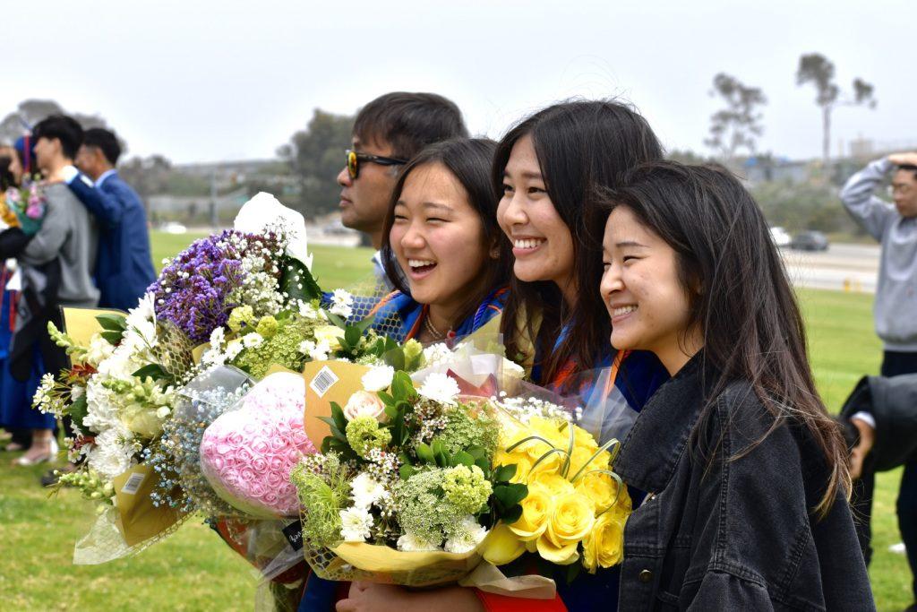 Two new alumni smile for a picture with their friend after the ceremony. Graduates and their families gathered on alumni to get their scenic celebratory photos.