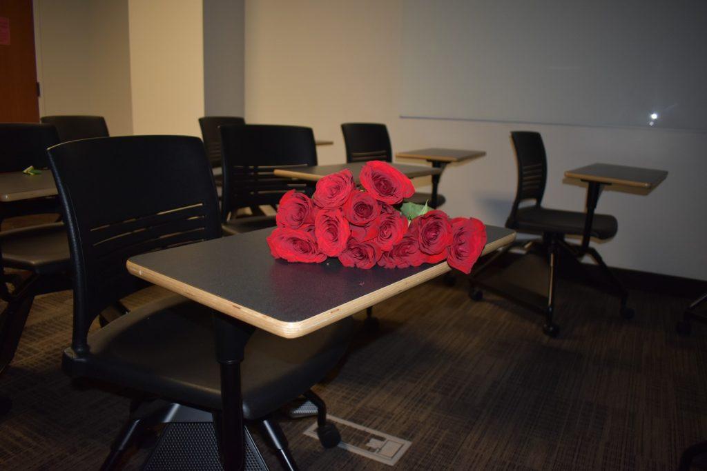 Roses lay on a desk in a classroom — a symbol of love in classrooms for Asha, Deslyn, Niamh and Peyton.